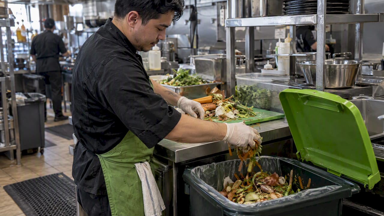 Worker sorting food scraps at prep station